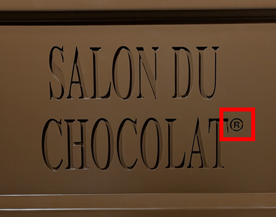 チョコレート形のパネルの拡大写真。パネルには「SALON DU CHOCOLAT」と刻まれており、その右上には商標登録を示すアールマークが刻まれている。